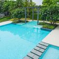 Modern outdoor swimming pool with turquoise water, stepping stones, and lush green landscaping