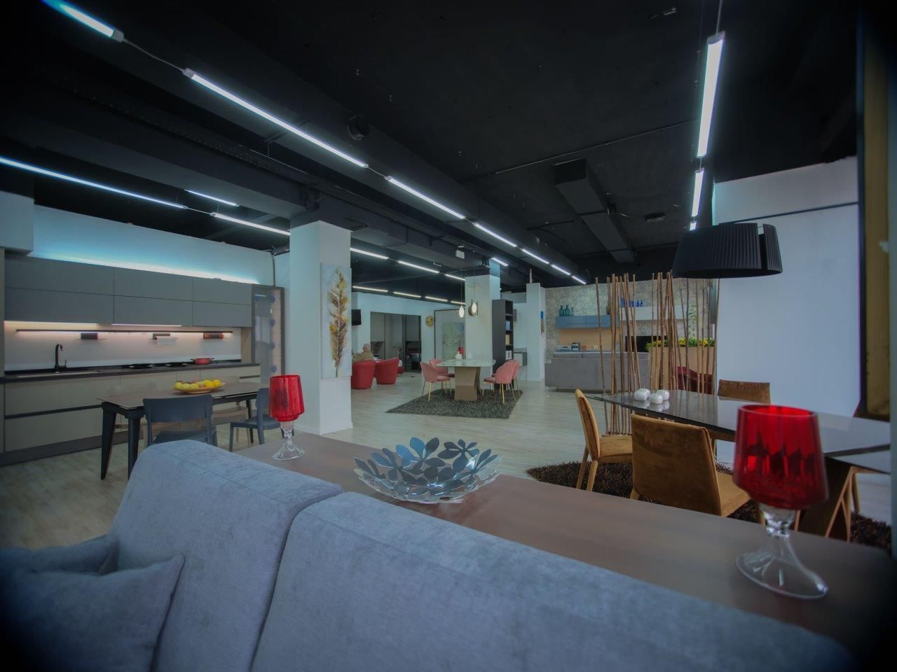 Ampio loft moderno con cucina a vista, zona pranzo e soggiorno, arredato con divani grigi e decorazioni minimaliste.