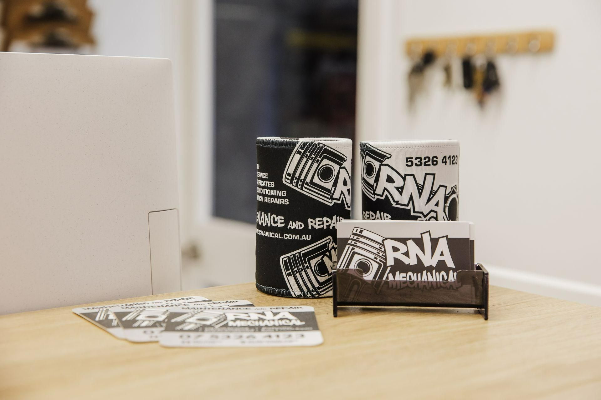 Two Business Cards Are Sitting On A Wooden Table — RNA Mechanical In Yandina, QLD
