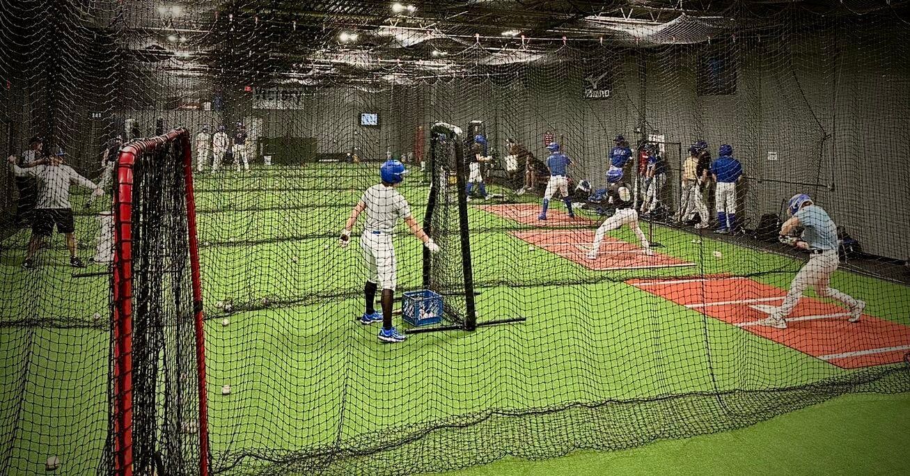 A group of people are playing baseball in a cage.