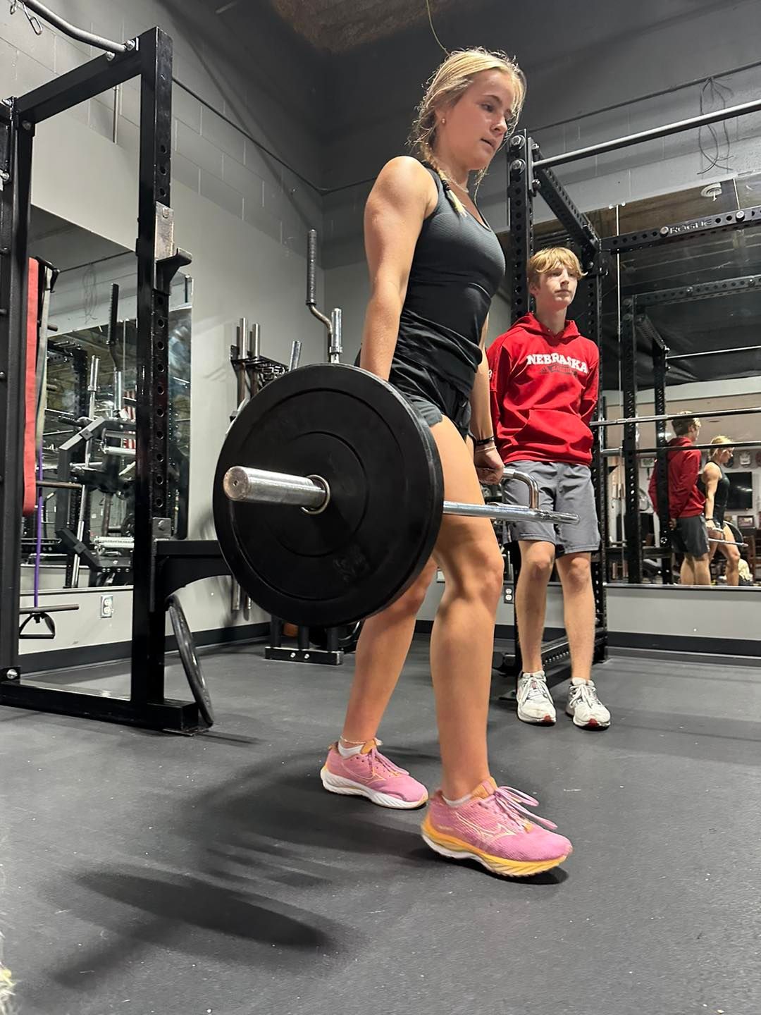 A woman is lifting a barbell in a gym.