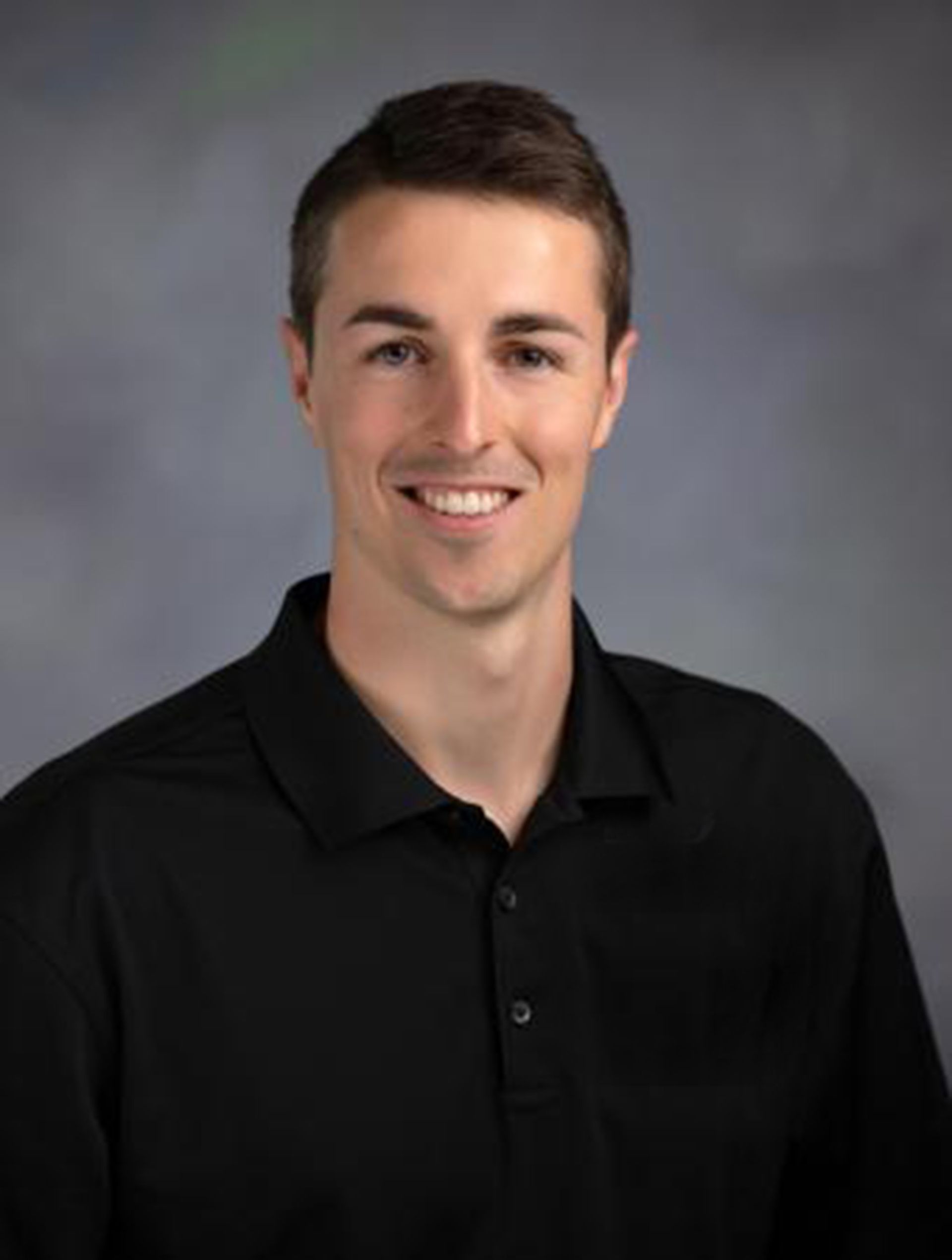 Dr. Austin Horan, DT, DPT in a black shirt is smiling for the camera.