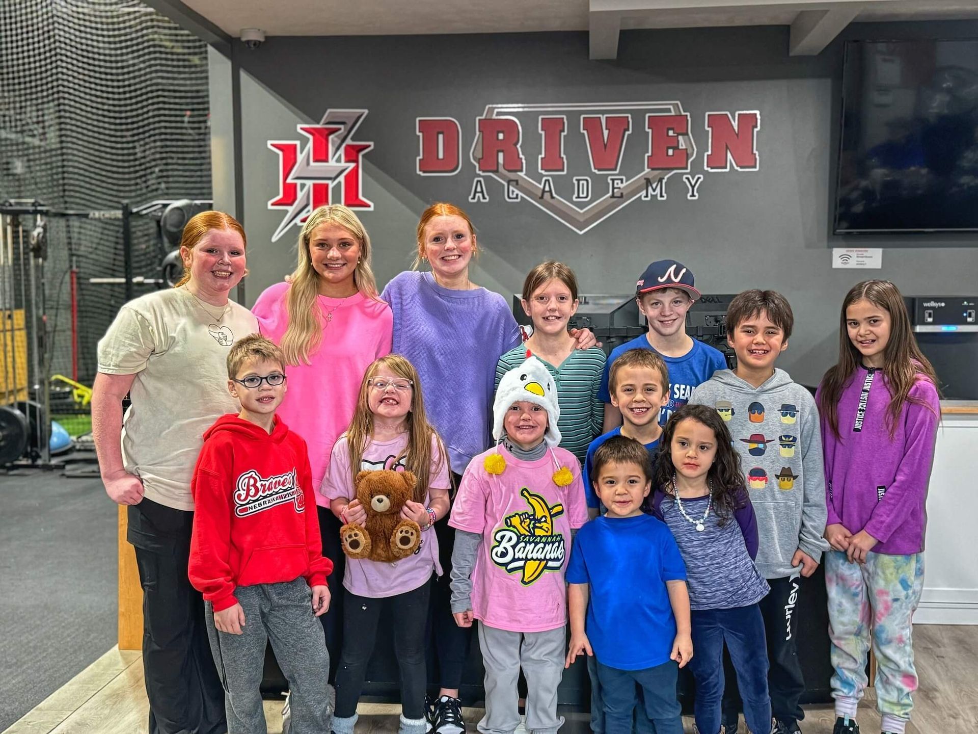 A group of children are posing for a picture in front of a sign that says driven academy.