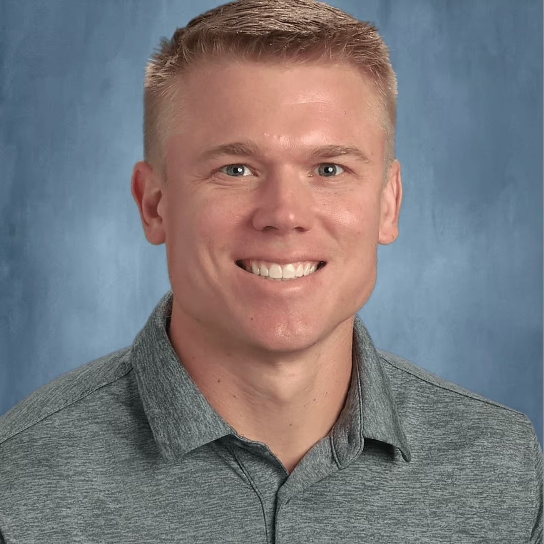 A man in a grey shirt is smiling for a picture.