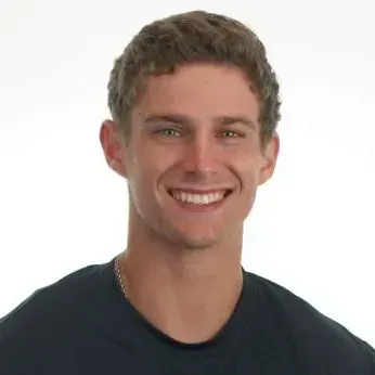 Smiling young man with light brown hair, wearing a dark blue shirt.