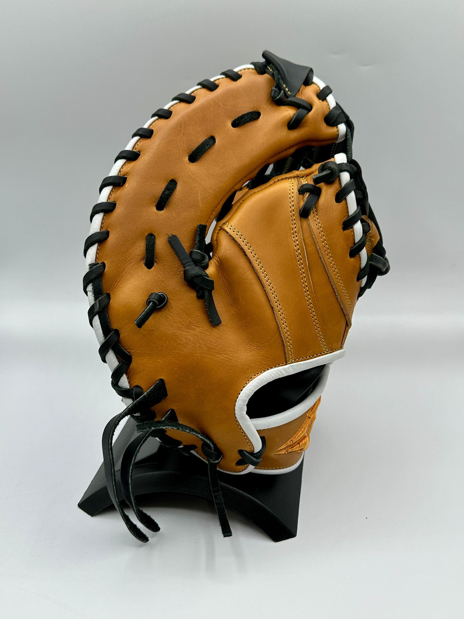A brown baseball glove is sitting on a black stand