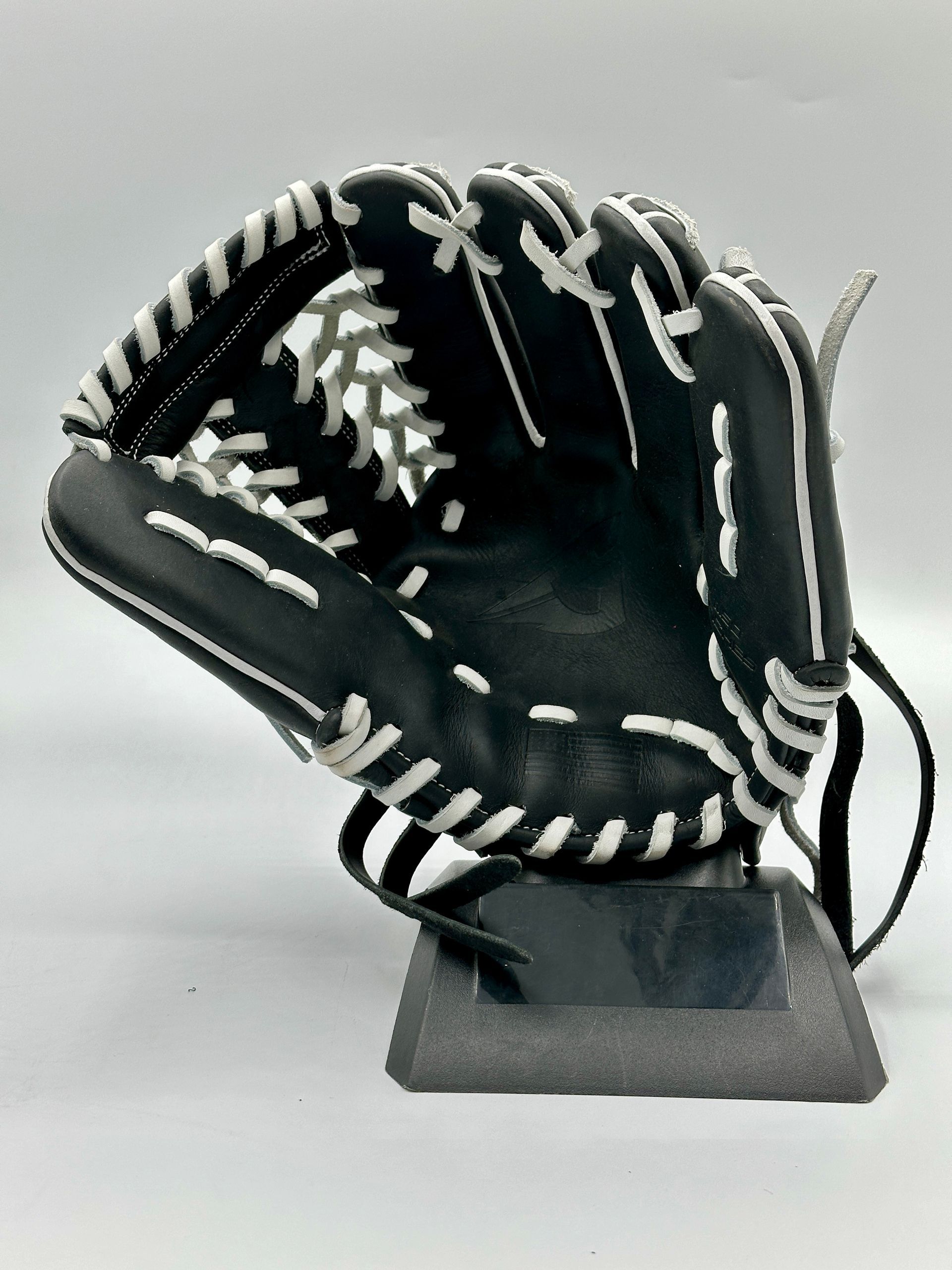 A black and white baseball glove is sitting on a stand.