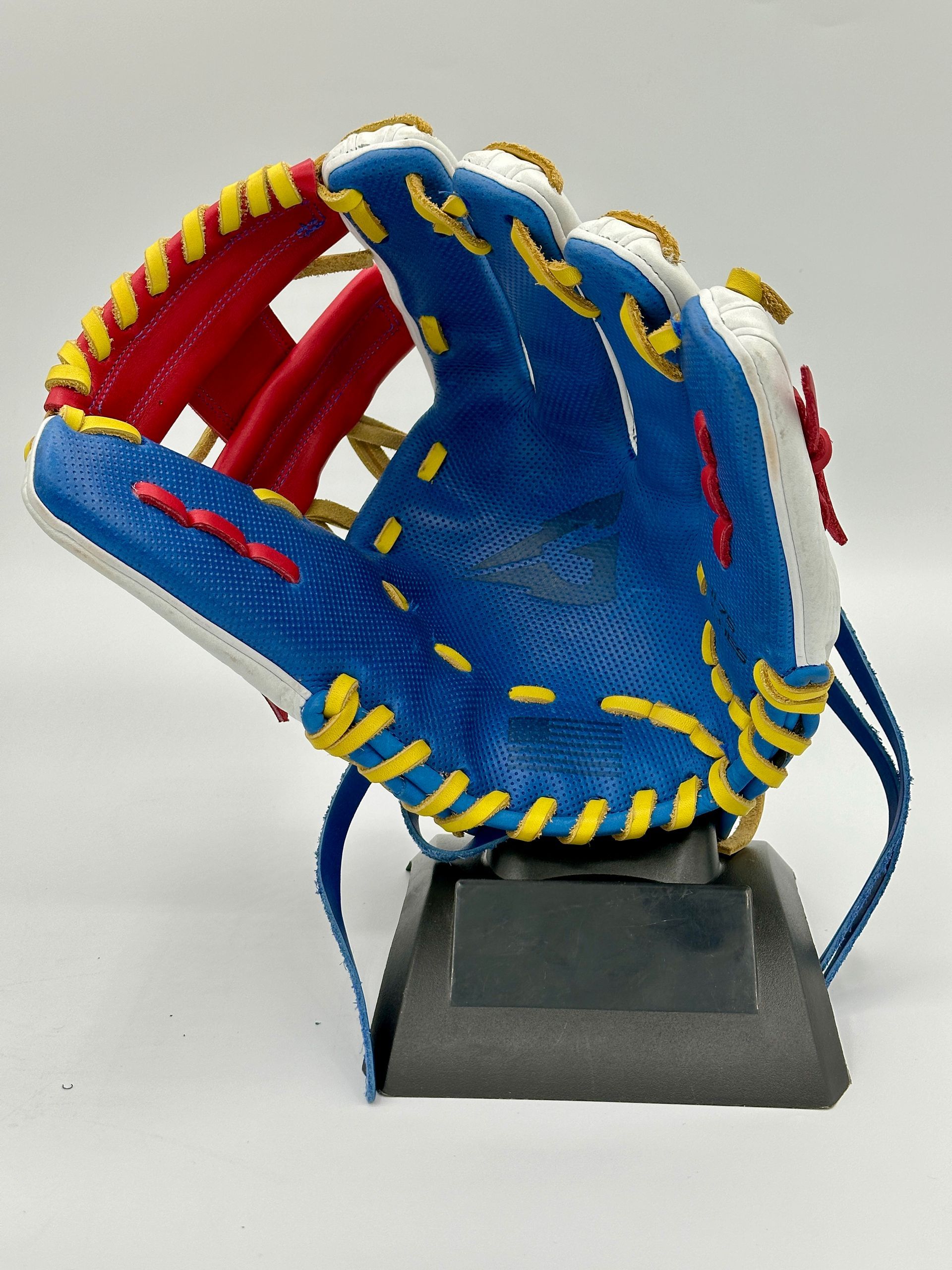 A blue and yellow baseball glove is on a stand