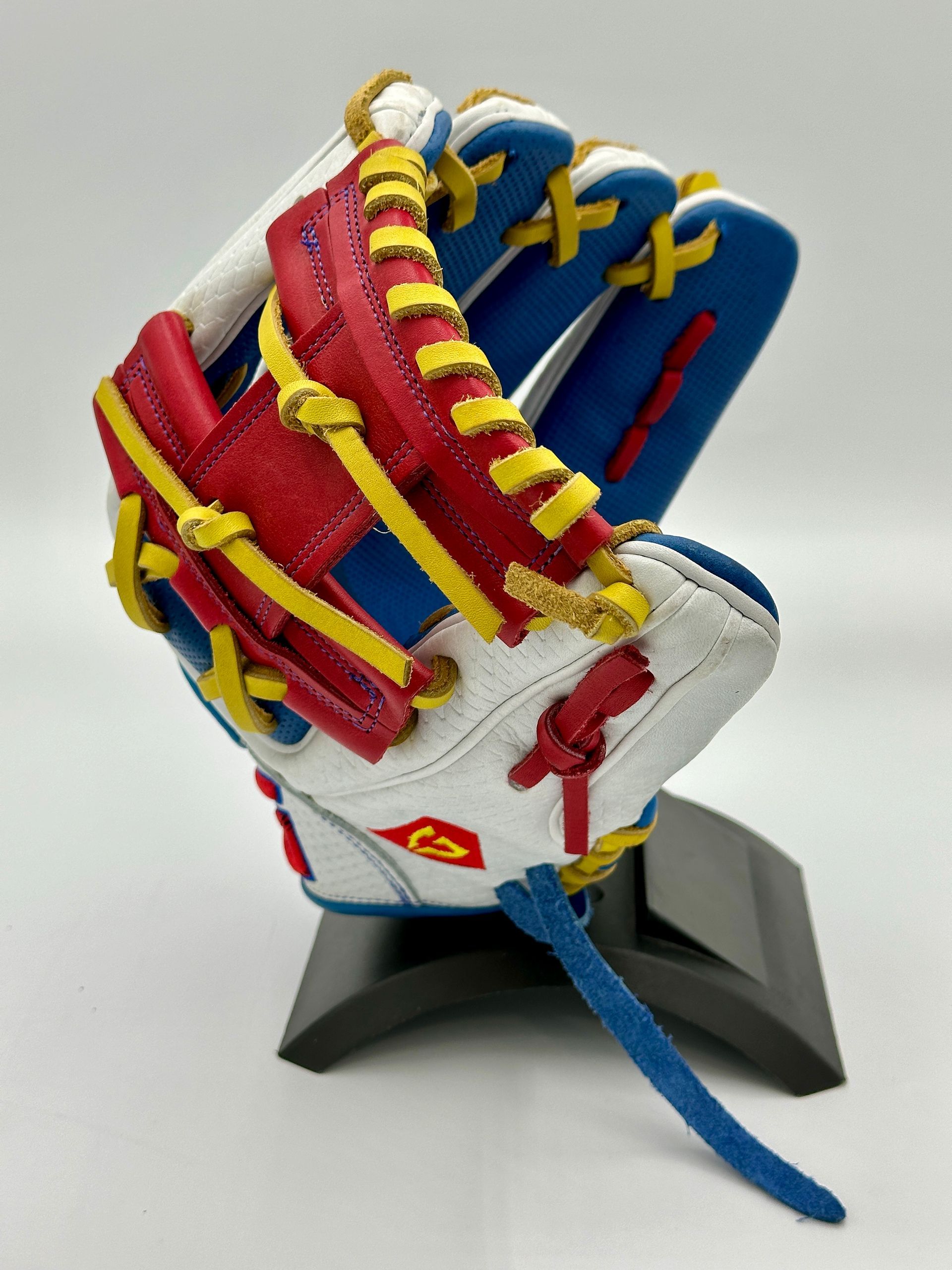 A red , white and blue baseball glove is sitting on a stand.