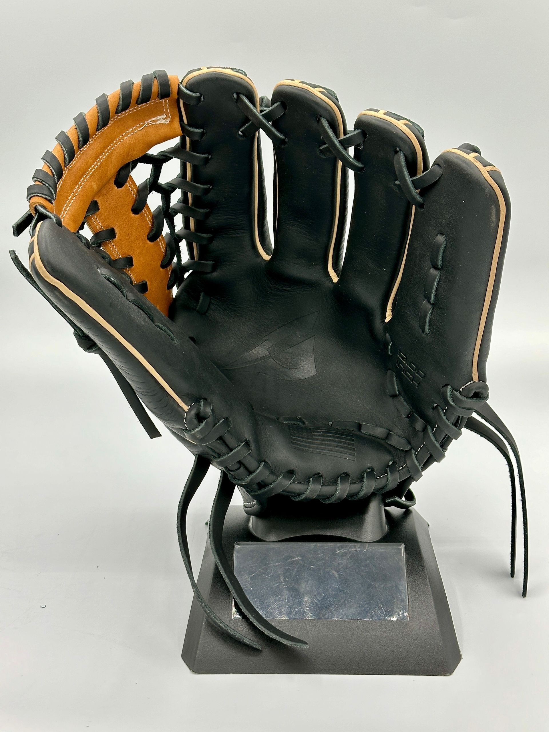 A black and orange baseball glove is sitting on a stand