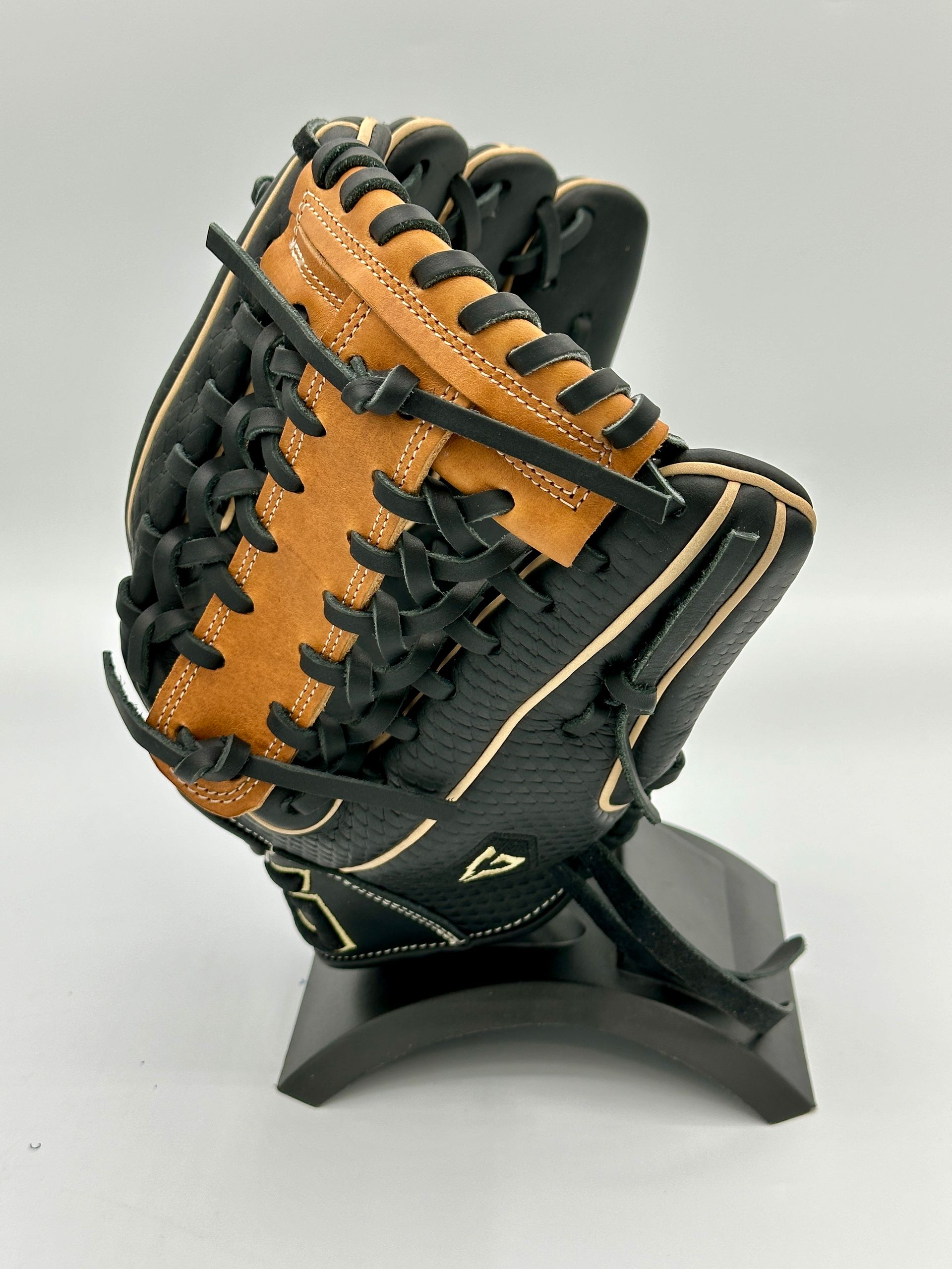 A black and brown baseball glove is sitting on a black stand.