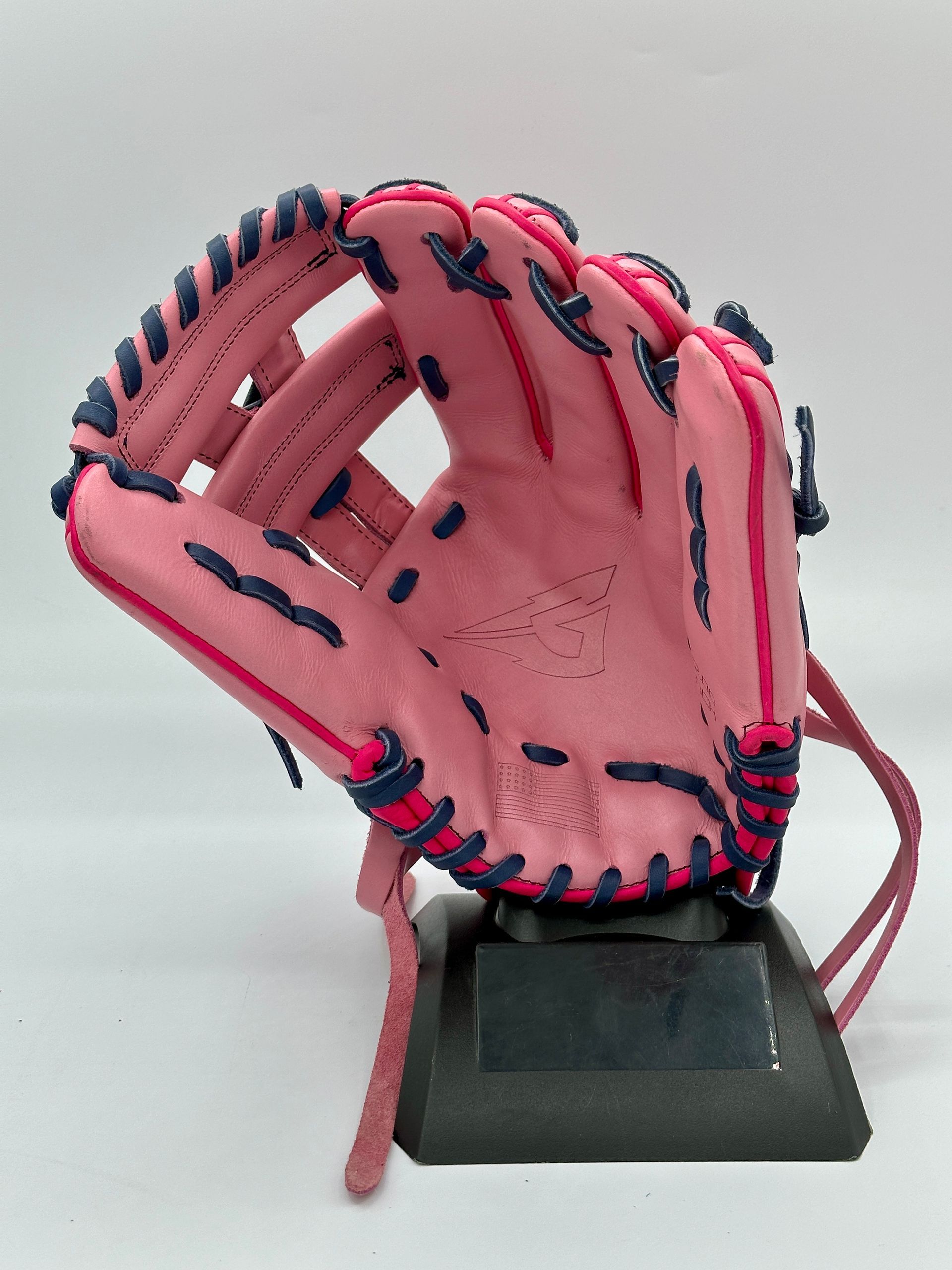 A pink baseball glove is sitting on a black base