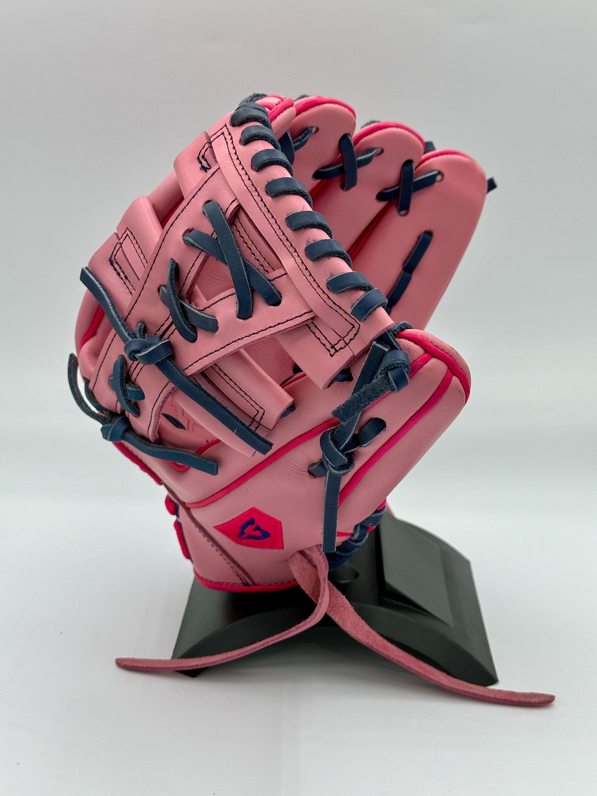 A pink baseball glove is sitting on a black stand