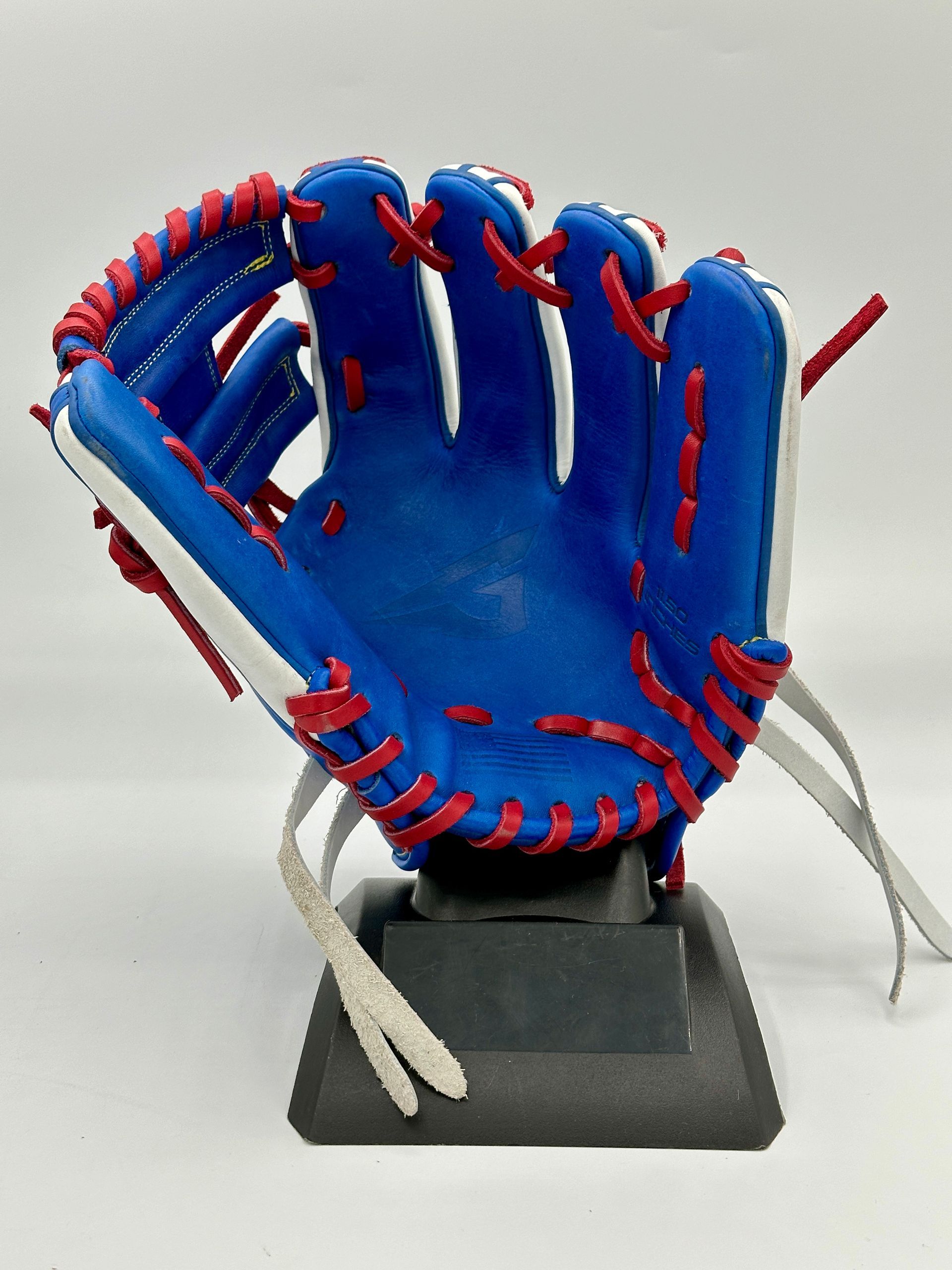 A blue baseball glove with red white and blue laces