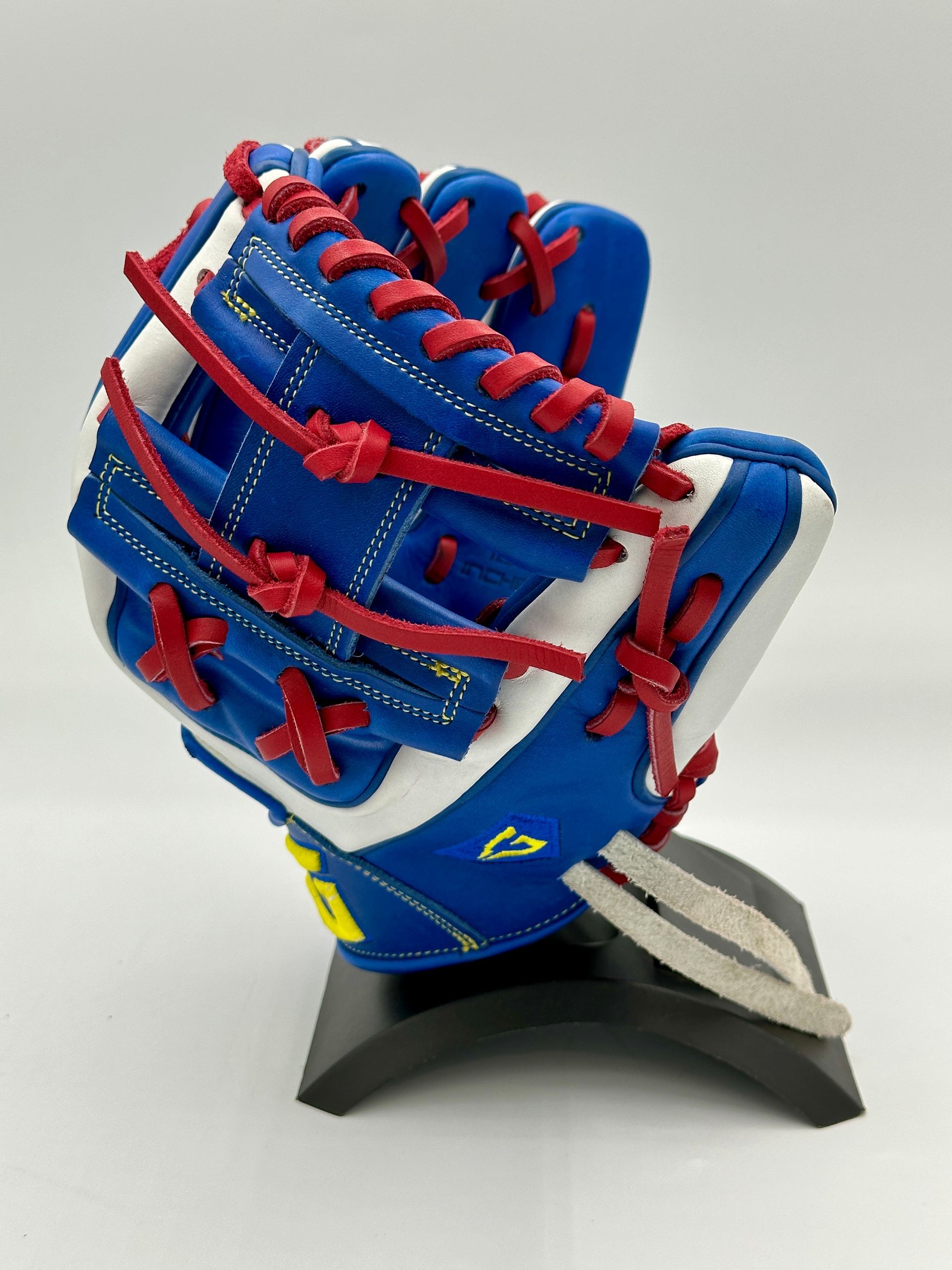 A blue and white baseball glove with red laces is on a stand.