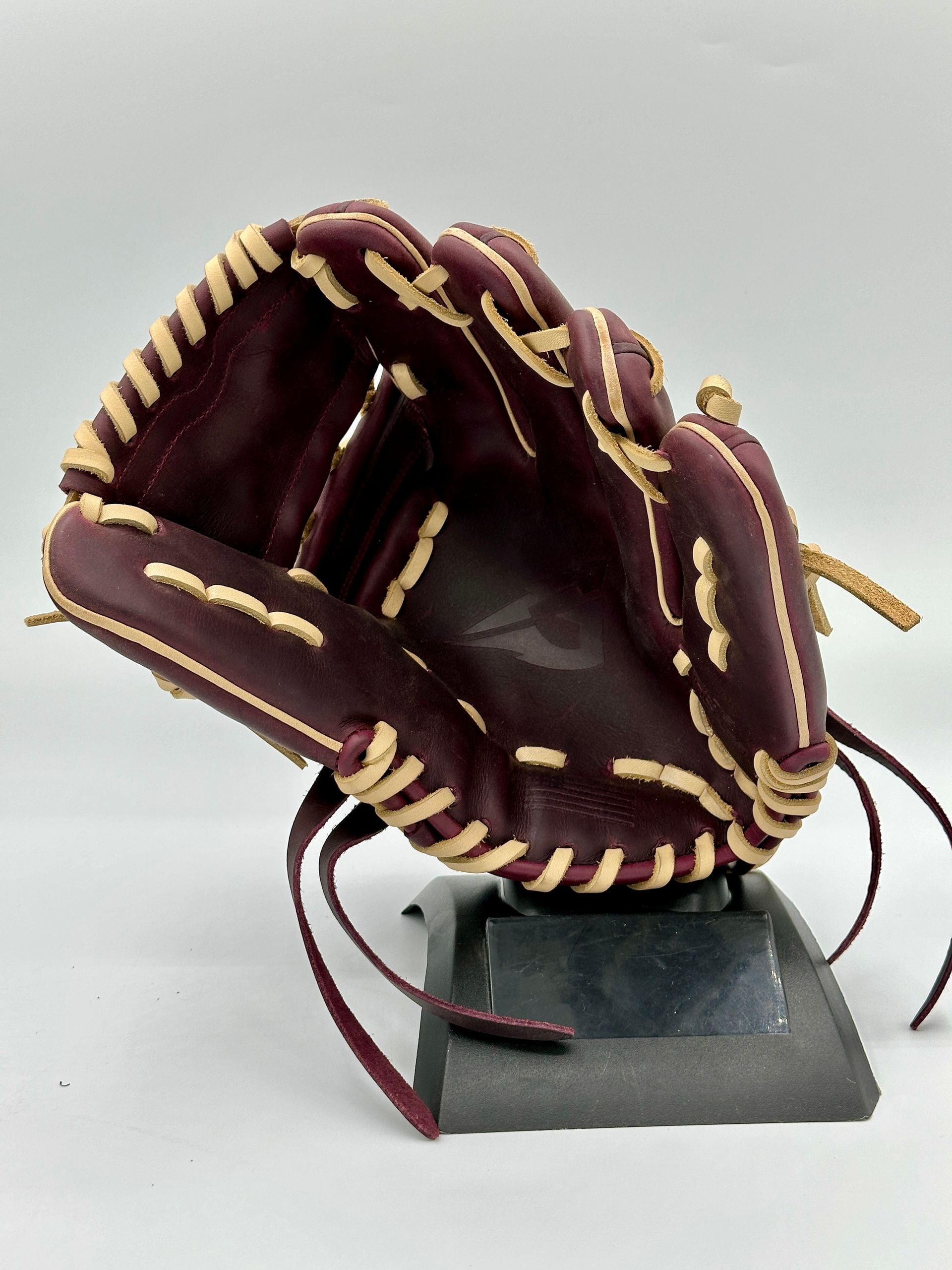 A maroon baseball glove is sitting on top of a trophy.