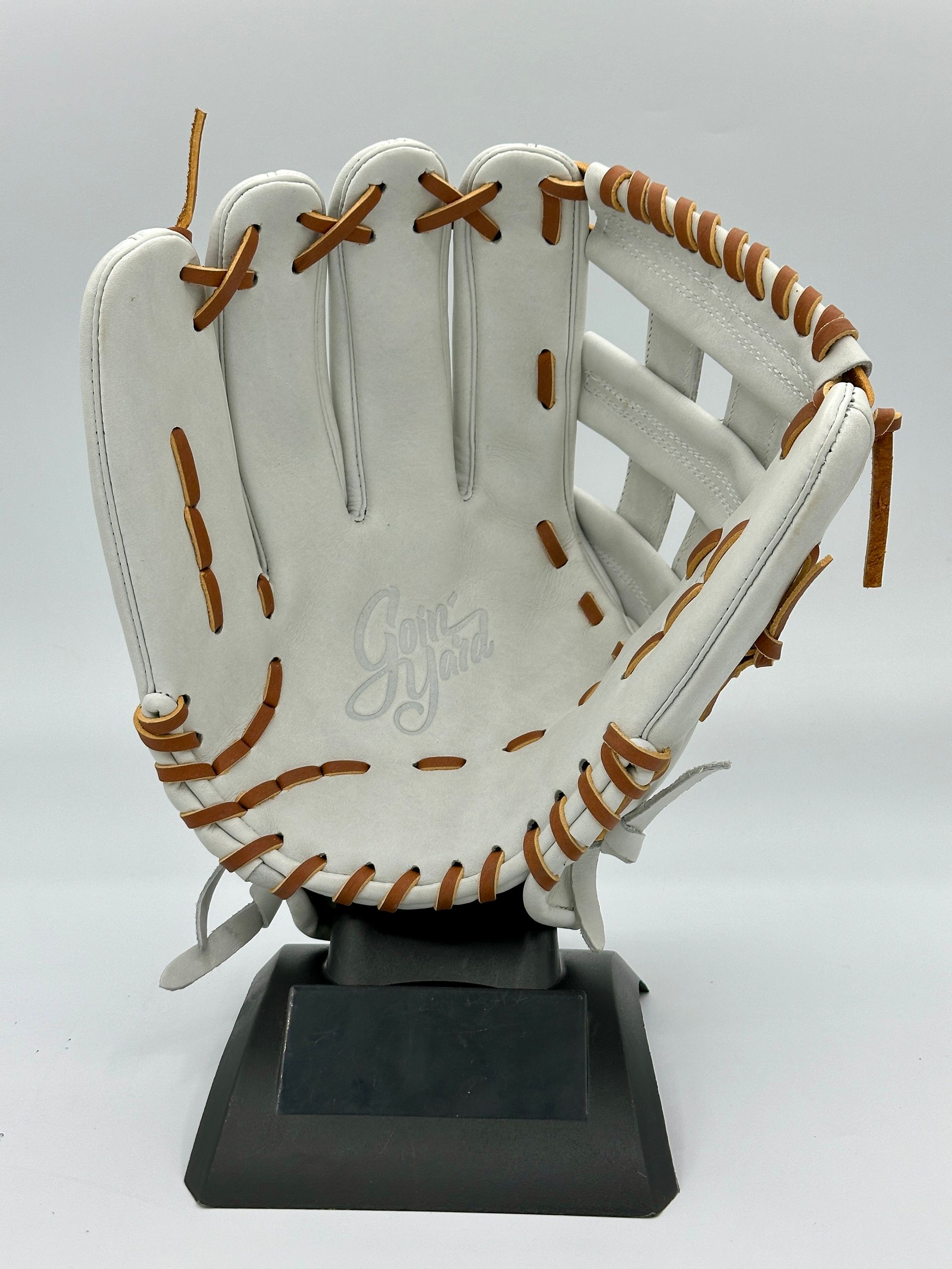 A white baseball glove is sitting on a black stand