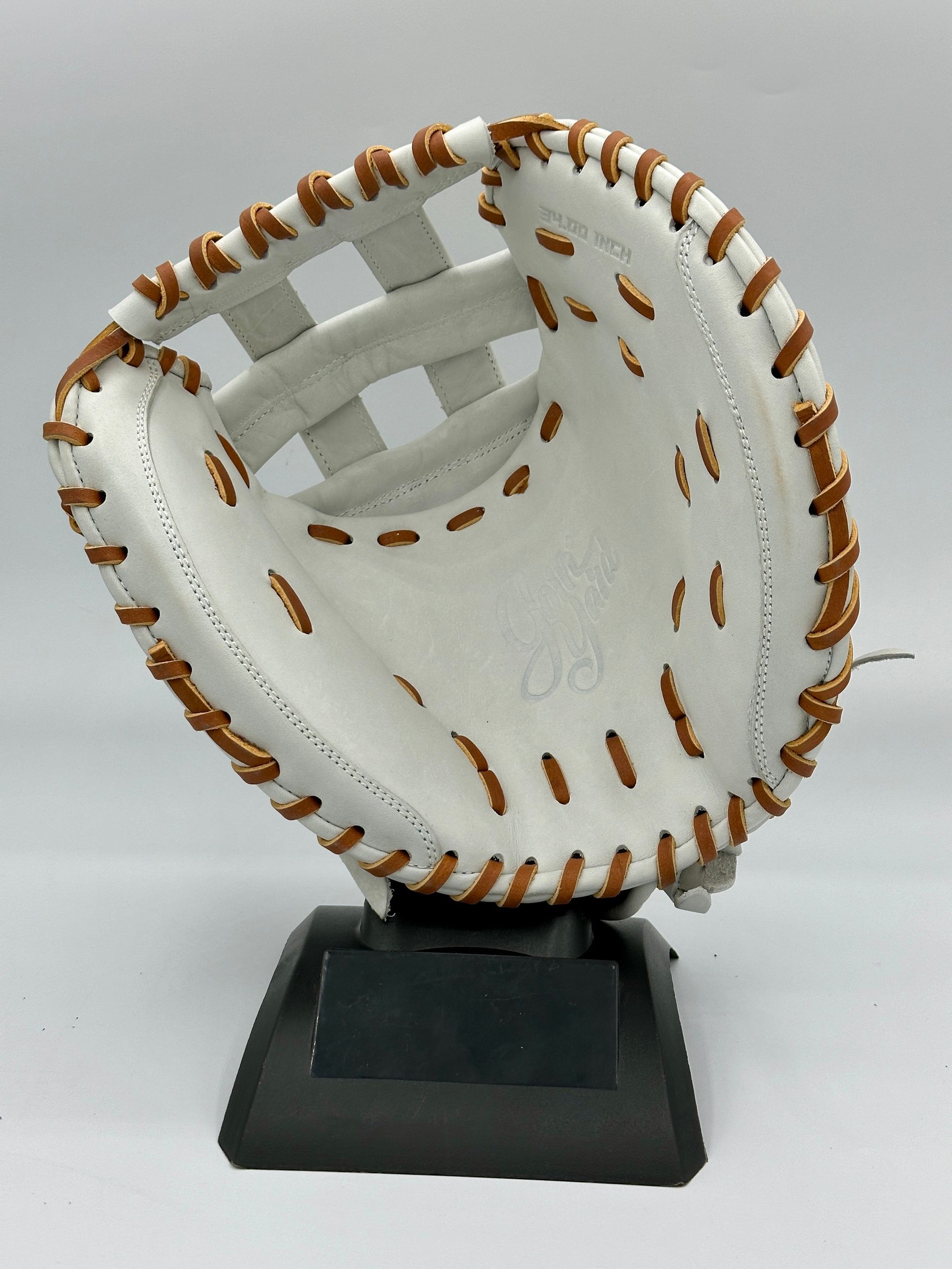 A white baseball glove with brown stitching sits on a black base