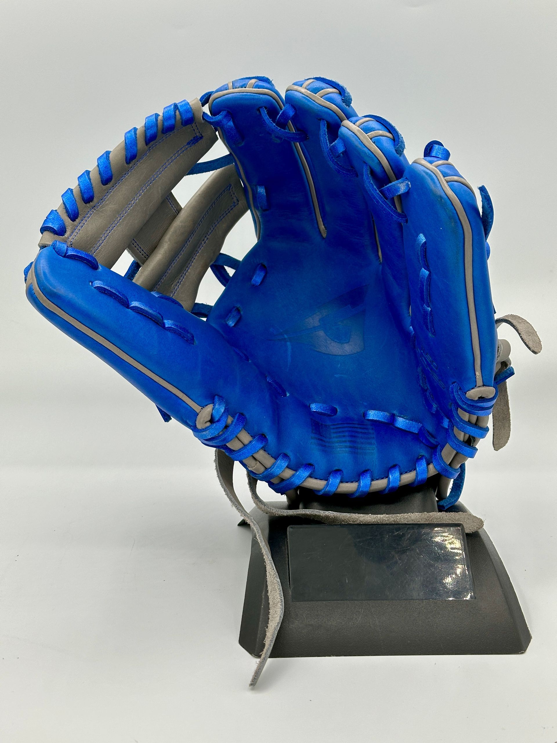 A blue baseball glove is sitting on top of a black base.