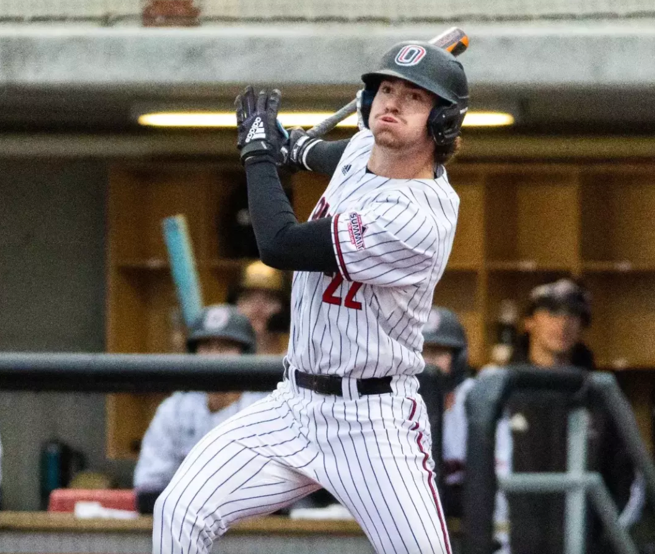 Baseball player in a striped uniform, holding a bat, looking focused.