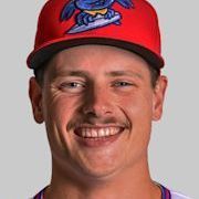 Man smiling, wearing a red baseball cap with a surfing creature on it.
