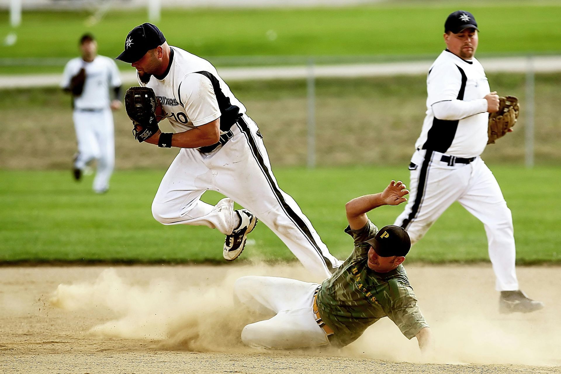 A baseball player is sliding into base while another player tries to catch the ball
