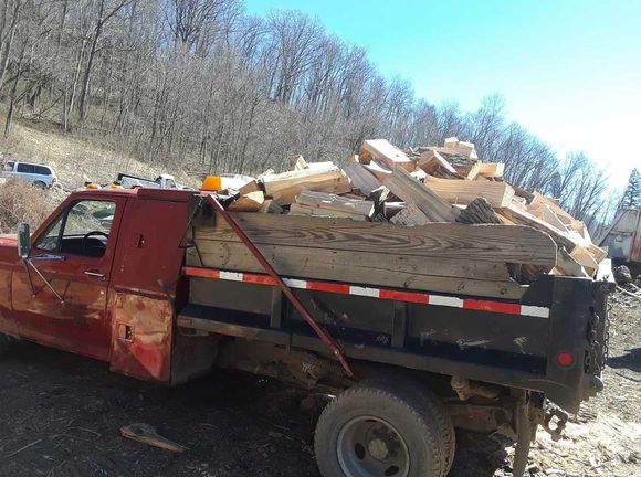 Red pickup truck loaded with firewood on a sunny day.