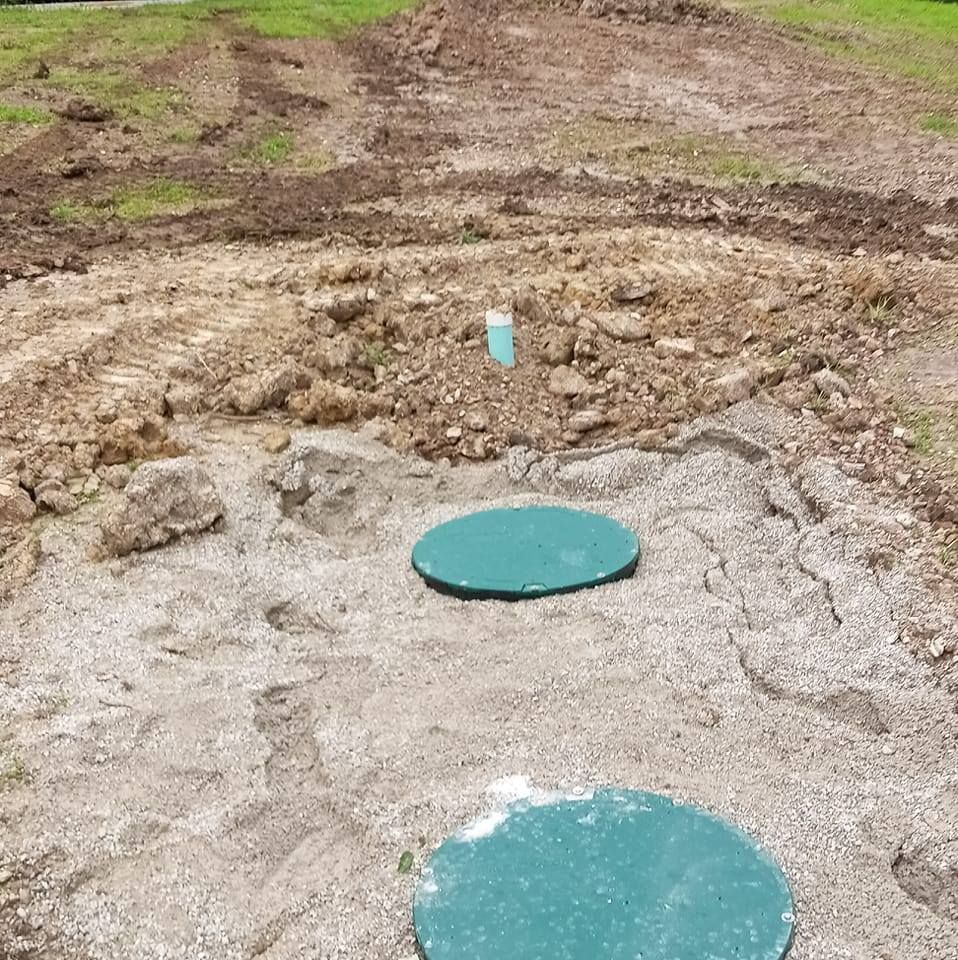 Manhole covers on a dirt path amid a muddy, excavated area
