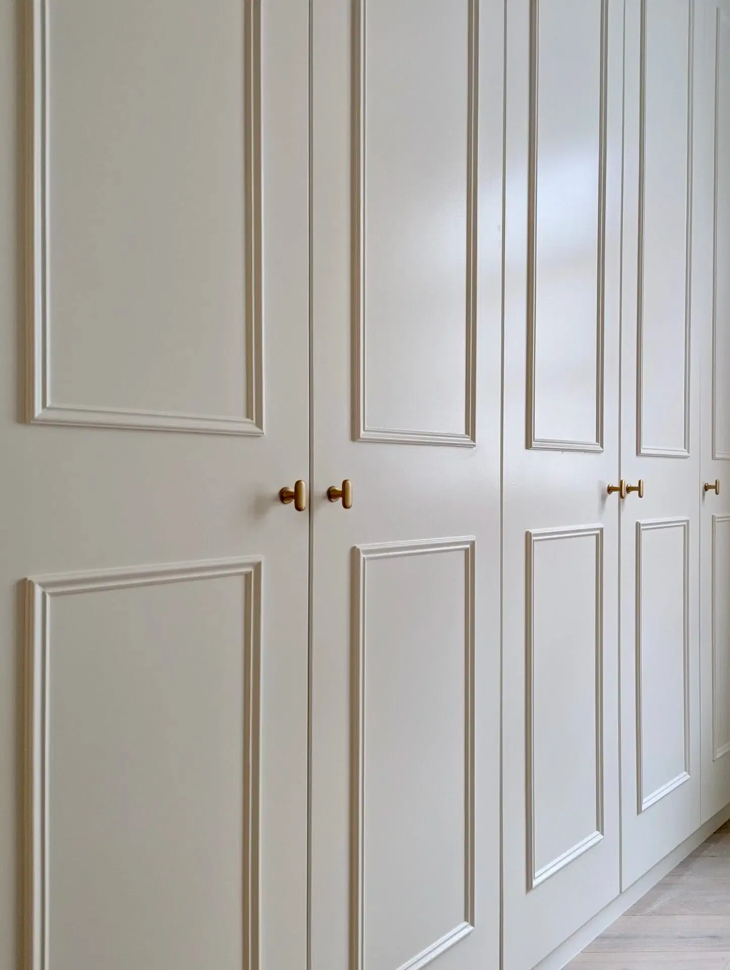 Cream-colored, paneled closet doors with gold knobs.