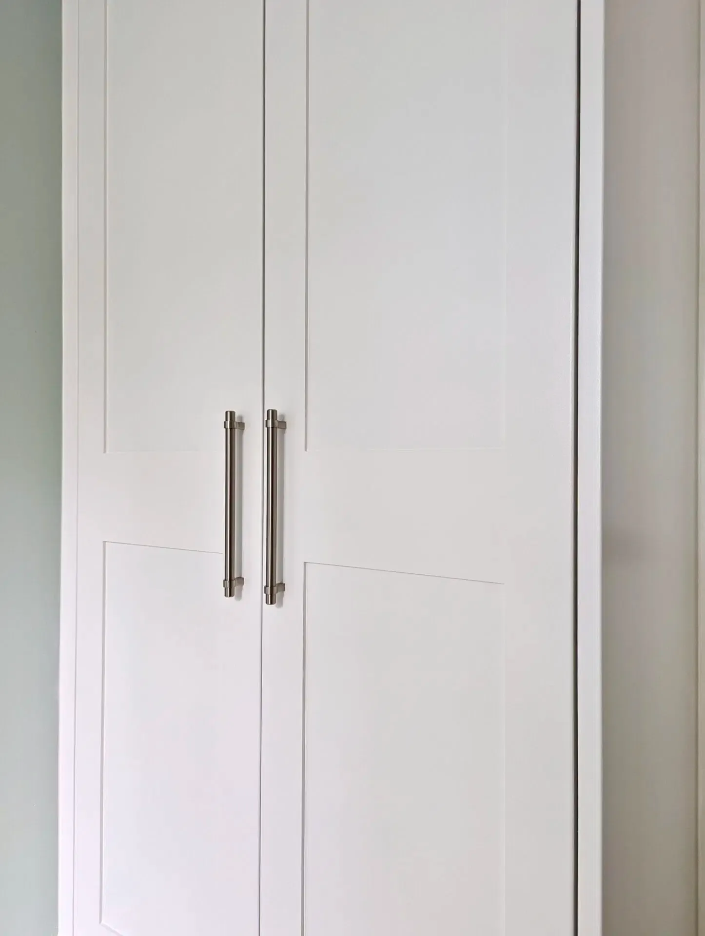 White closet with two doors and silver handles.