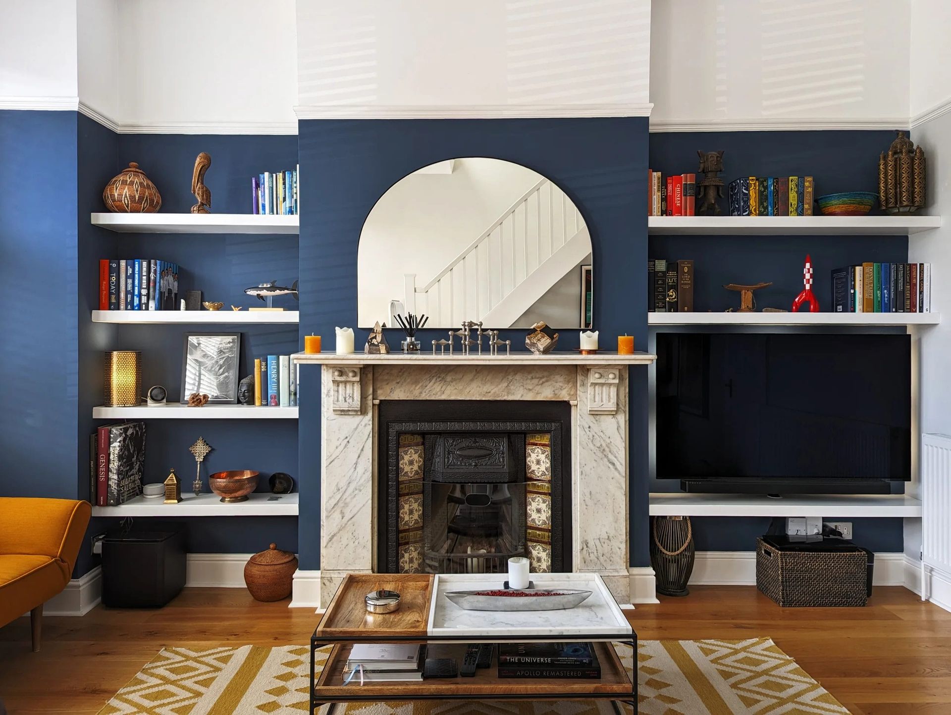 Living room with built-in bookshelves painted dark blue, a fireplace, and a large mirror.