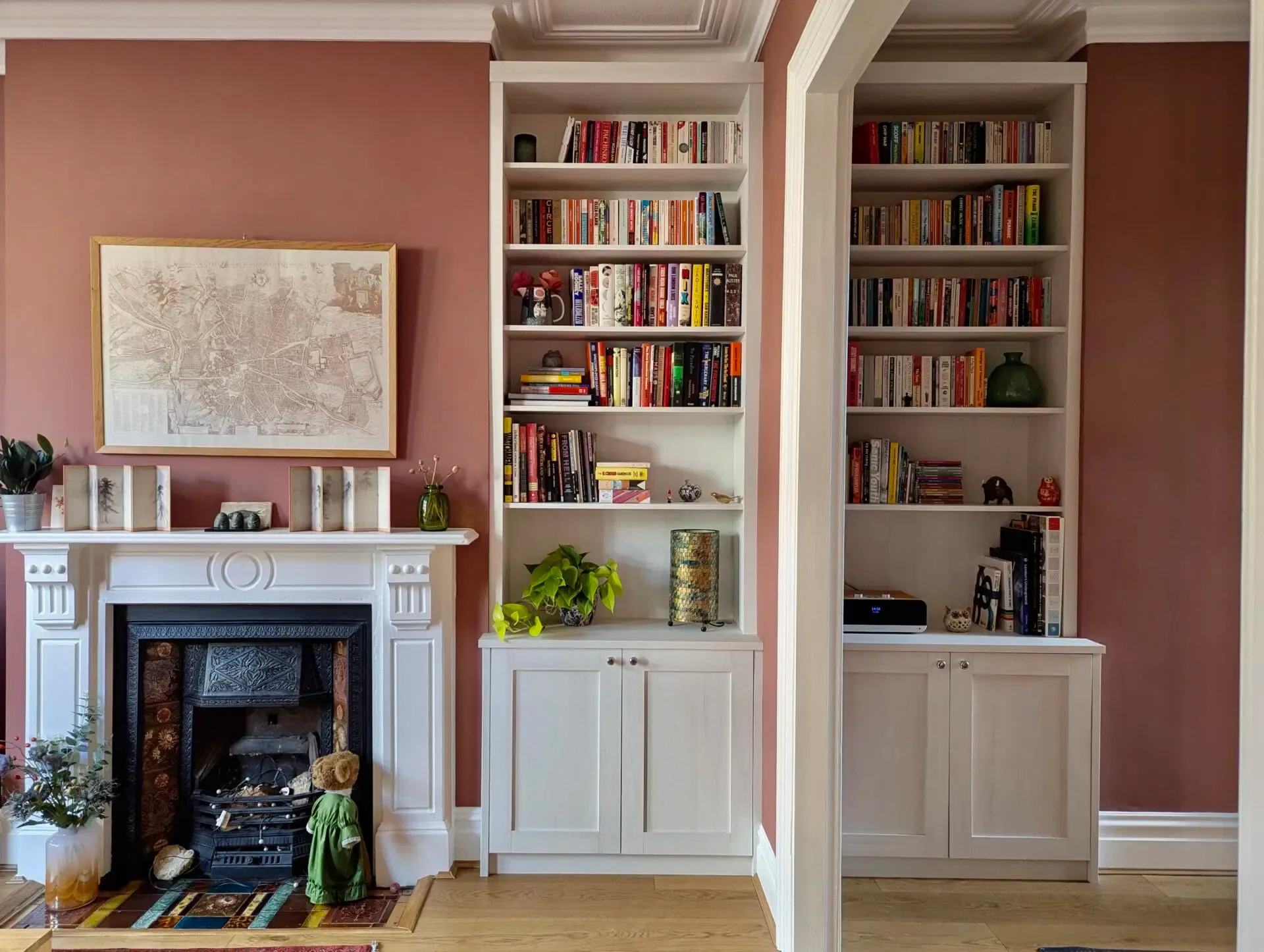 Living room with fireplace and built-in white bookshelves against a dusty rose wall.