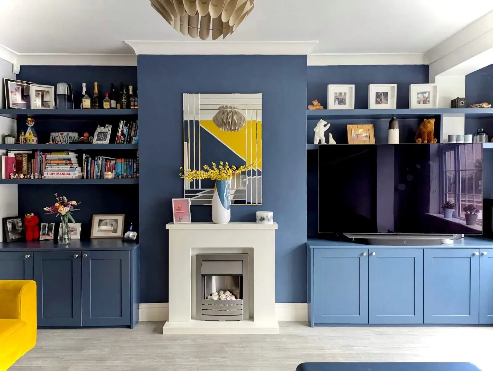 Living room with blue walls, white fireplace, built-in shelves, and a yellow sofa.