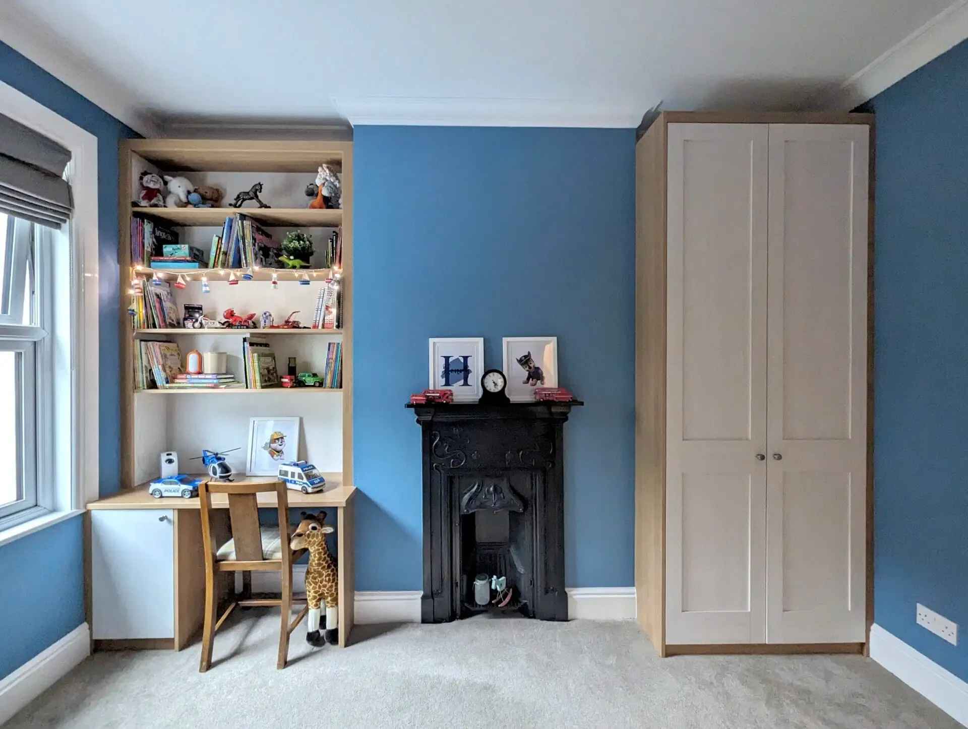 Blue-walled child's room with built-in desk, shelving, fireplace, and wardrobe.