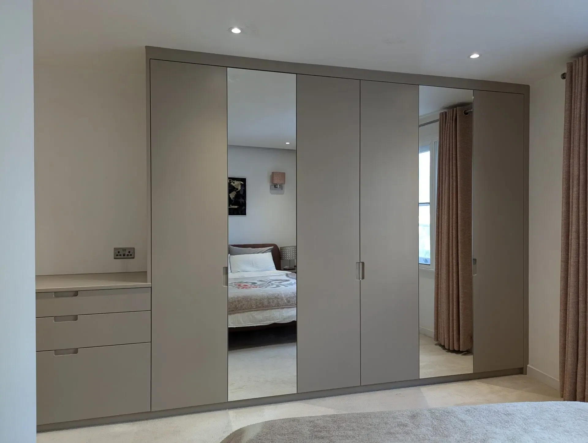 Beige modern closet with mirrored doors in a bedroom.