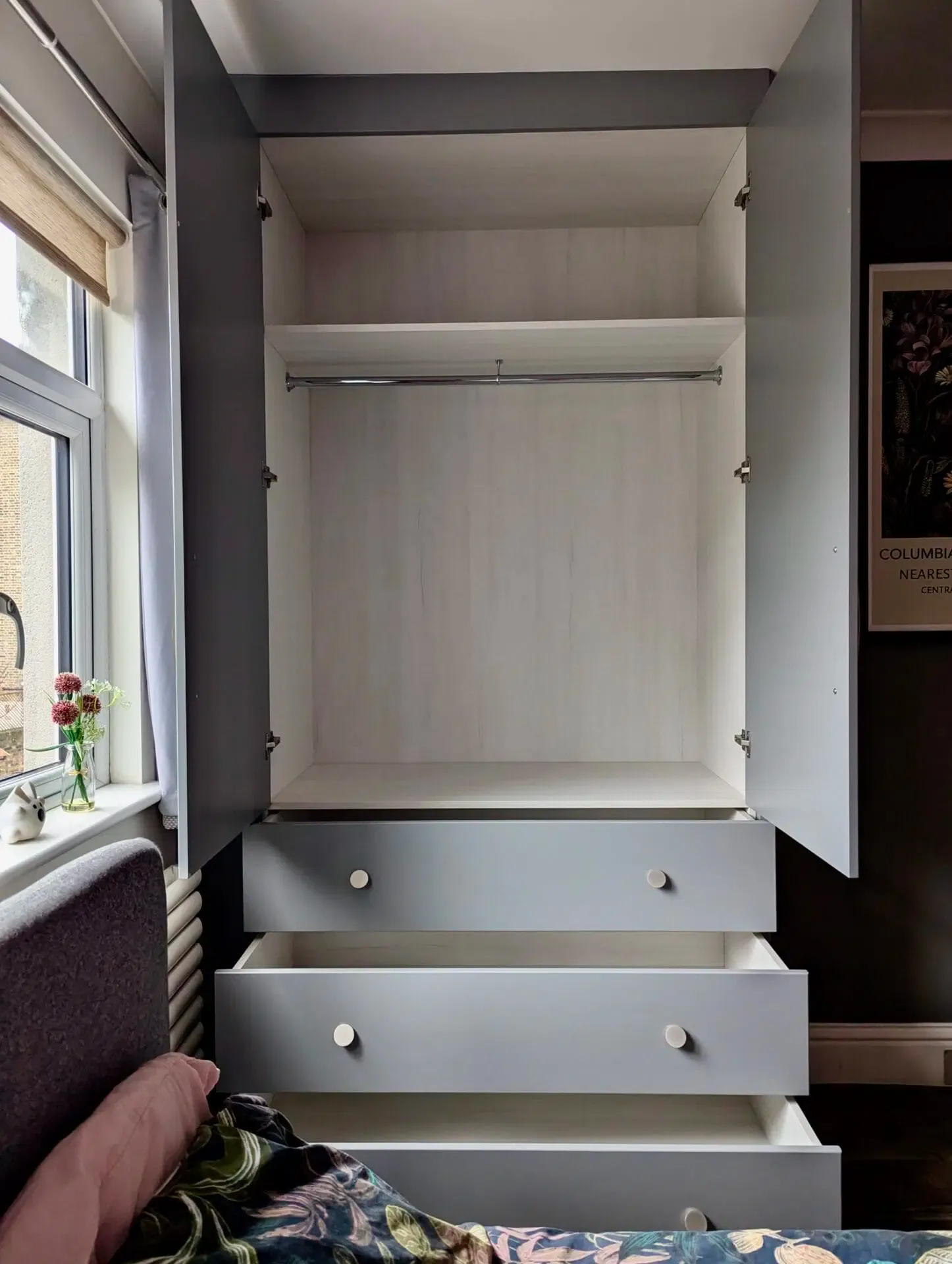 Gray and white wardrobe with open doors, drawers, and hanging rod.