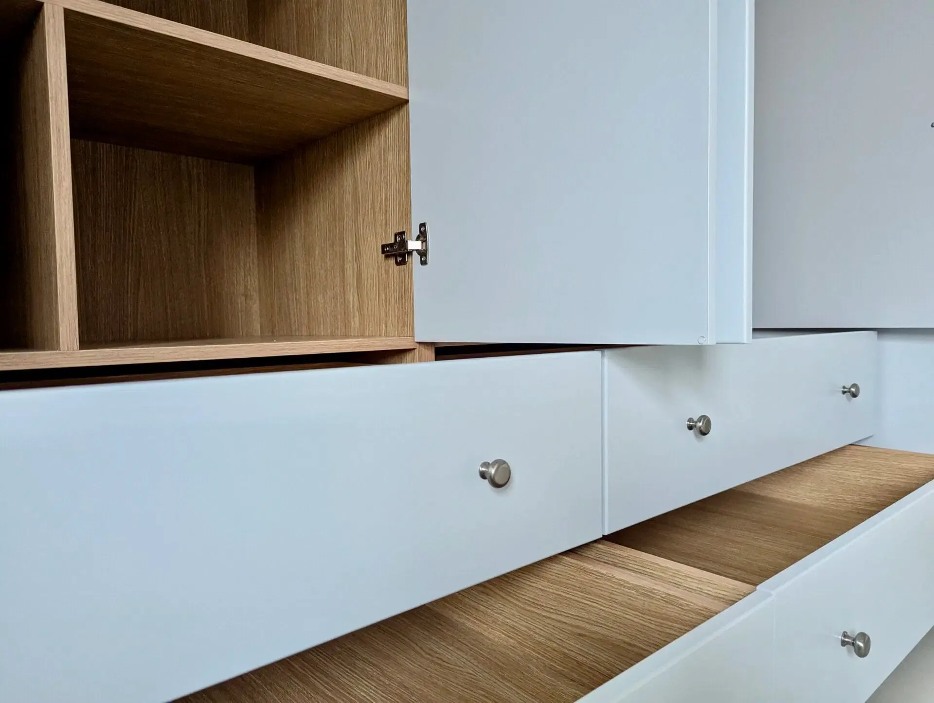 White cabinet with open drawer and wooden shelving.