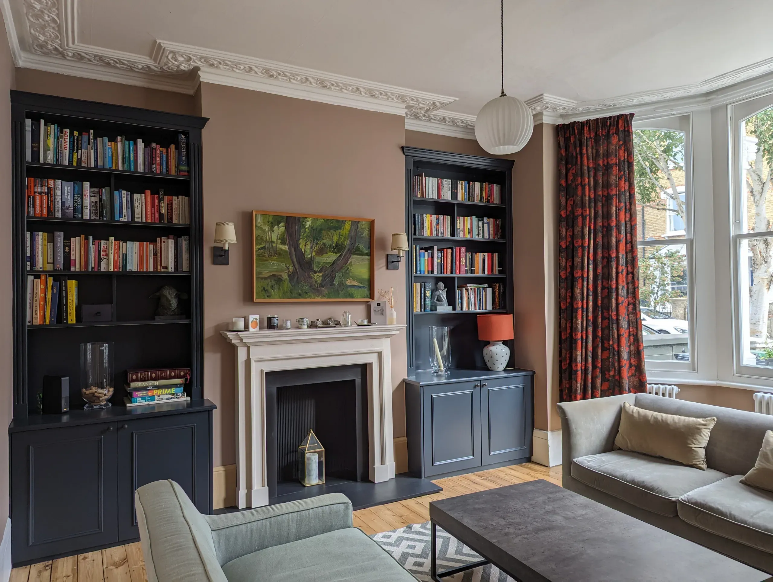 Living room with built-in bookshelves, fireplace, and sofa.  Dark blue bookshelves and neutral color walls.