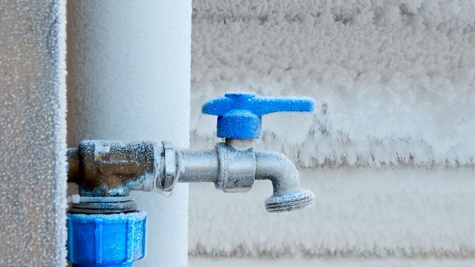 A close up of a water faucet with a blue handle on a wall.