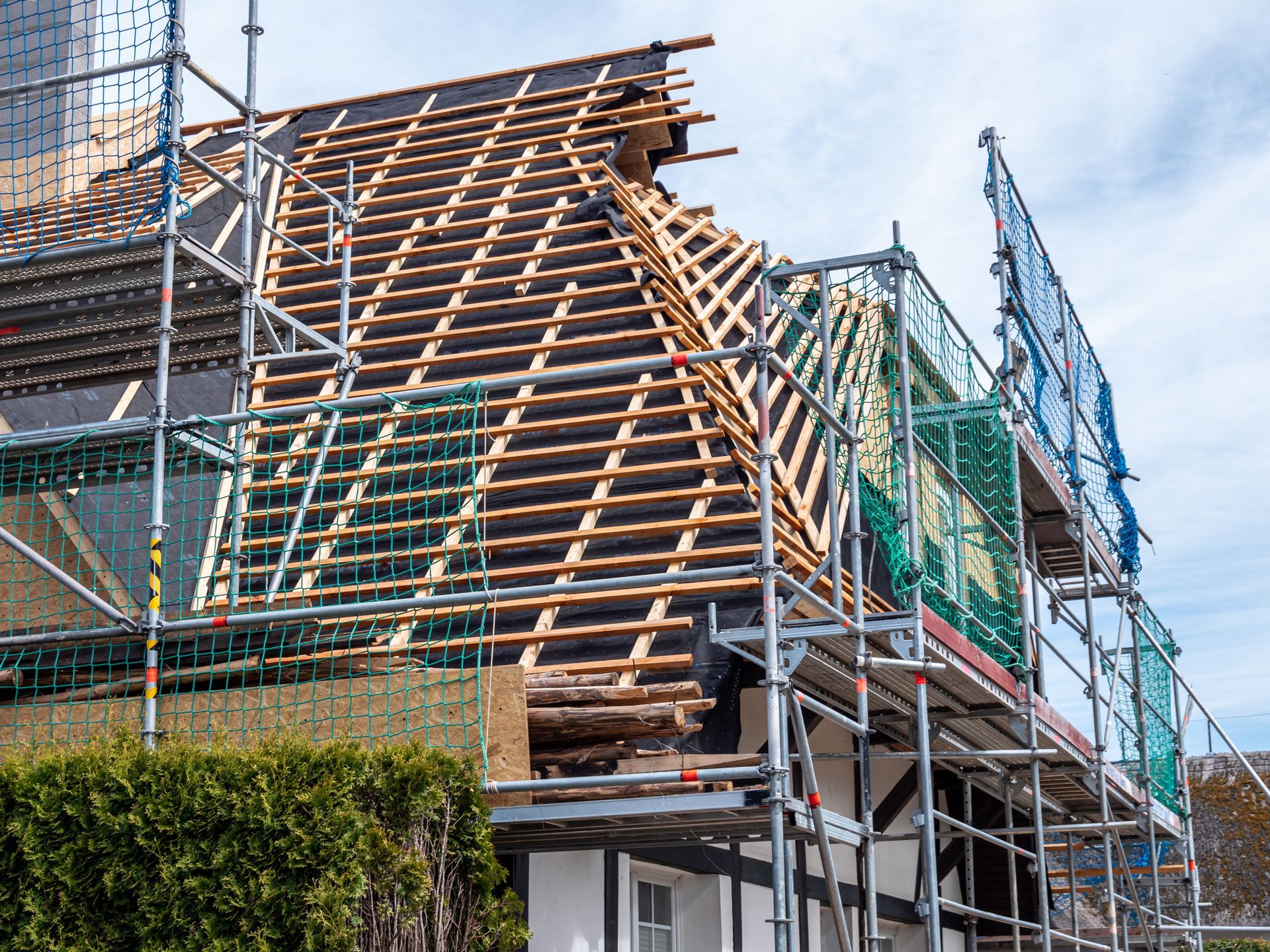 A house is being built with scaffolding and a wooden roof.