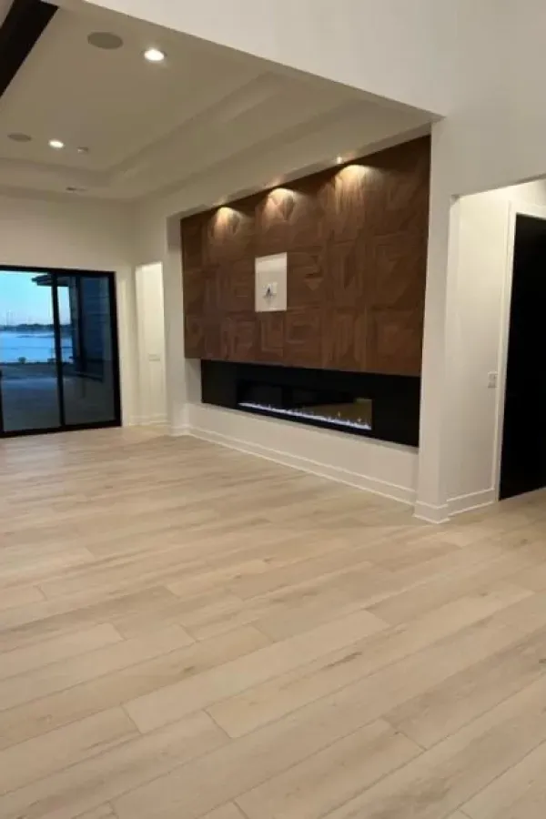An empty living room with hardwood floors and a fireplace.