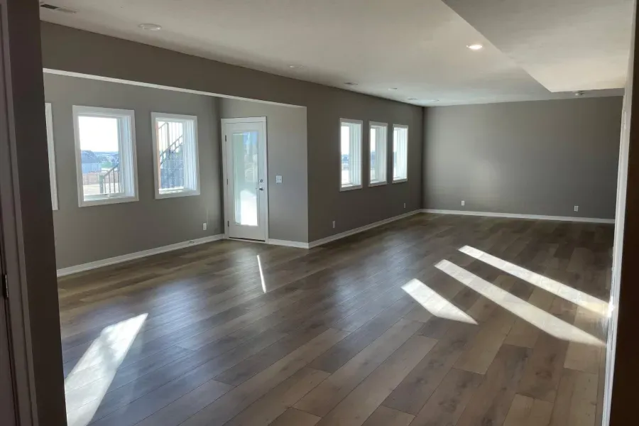 An empty living room with hardwood floors and gray walls