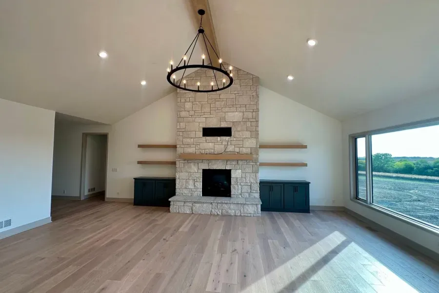 An empty living room with a fireplace and a chandelier.