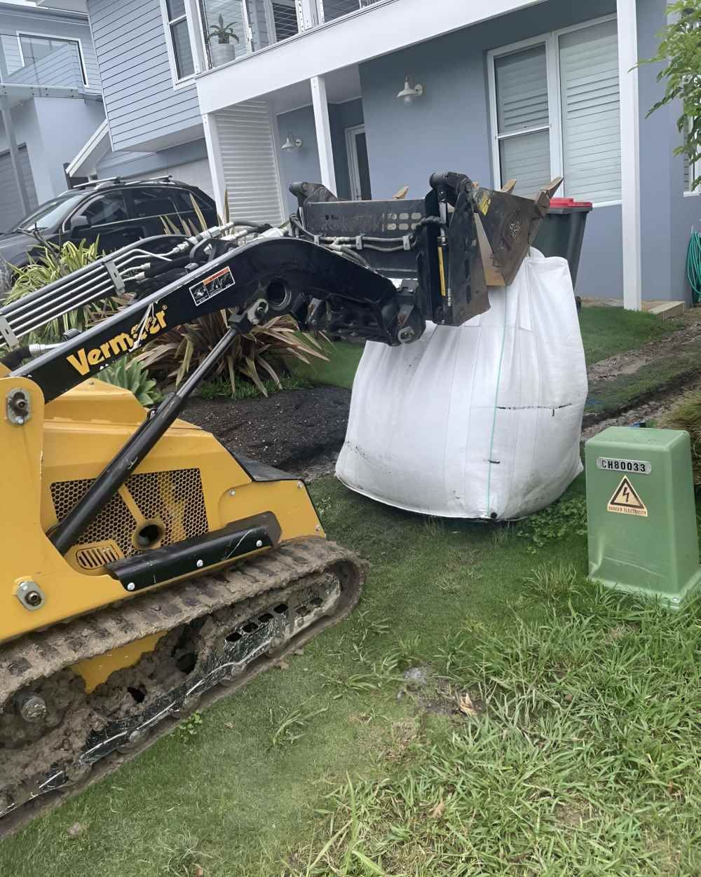 A Yellow Tractor with A Large Bag Attached to It — R&J Cronin Equipment Hire in Cooranbong, NSW