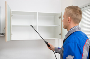 Technician inspecting open white wall cabinet with a flashlight-like tool
