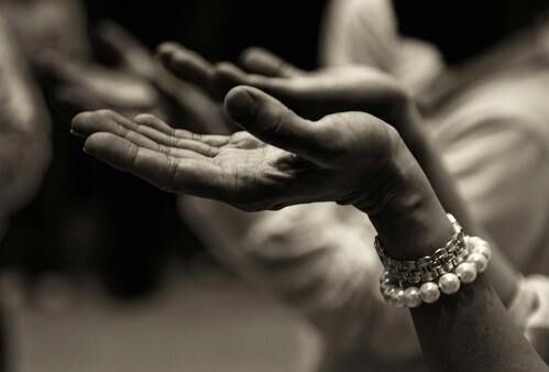 Hands cupped upward, wearing a bracelet, likely in prayer or supplication.