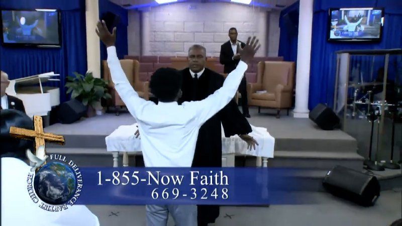 A person stands with arms raised facing a minister in a church, with a phone number displayed on a blue banner.
