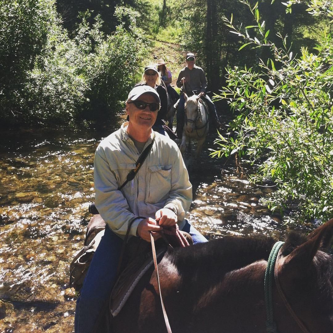 A man is riding a horse through a river