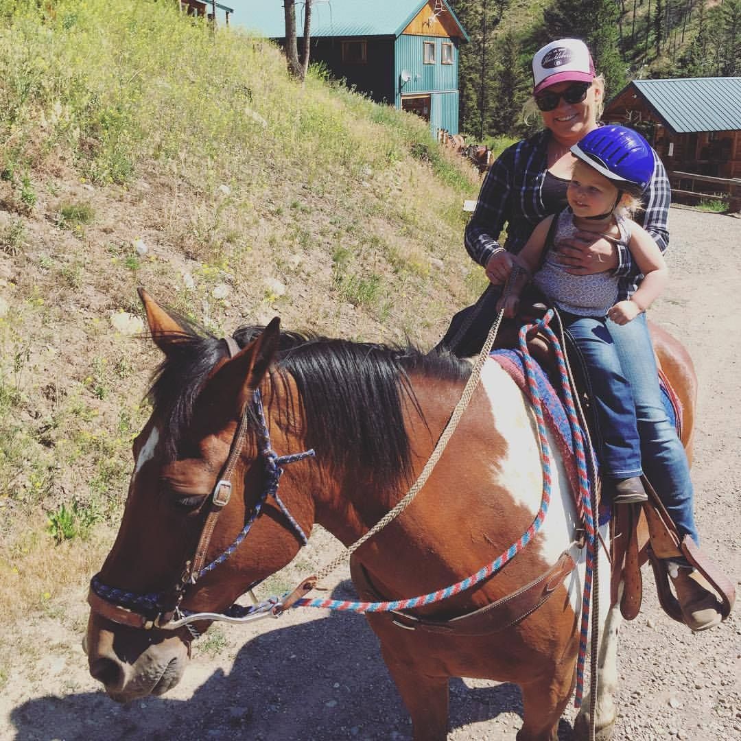 A woman and child are riding a brown and white horse