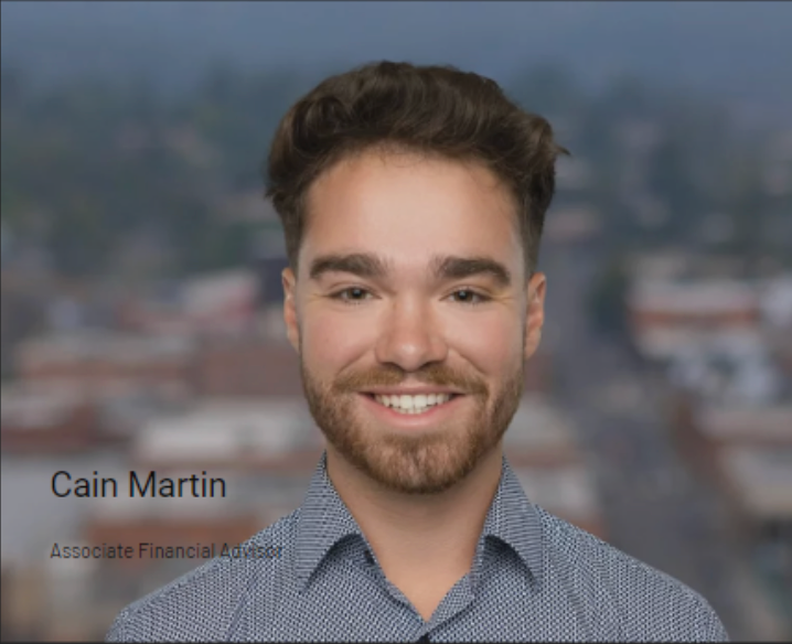 Portrait of Cain Martin smiling in a patterned shirt with a blurred cityscape background